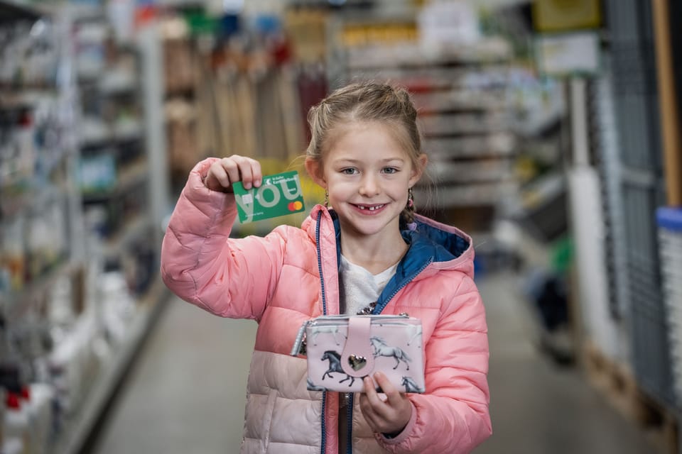 Ein junges Mädchen zeigt stolz Ihre Debit Mastercard You und ihren Geldbeutel